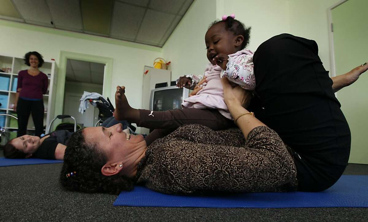 Kate Holcombe, founder of the Healing Yoga Foundation demonstrates a yoga pose with help from Aniyah Meadows age one and half. Holcombe conducted this workshop for Compass Family Services, which provides housing for homeless families Wednesday September 21, 2011 in San Francisco. Holcombe is part of a new documentary, Yogawoman, narrated by Annette Bening that features many Bay Area yoga instructors.