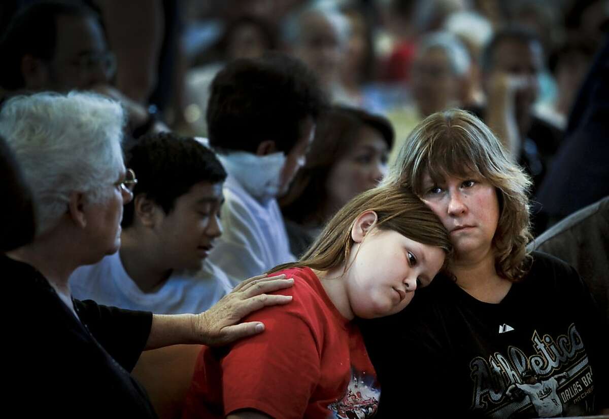 Jessica Sherwin, 11, is comforted by her mom, Michelle, and others at a community meeting.