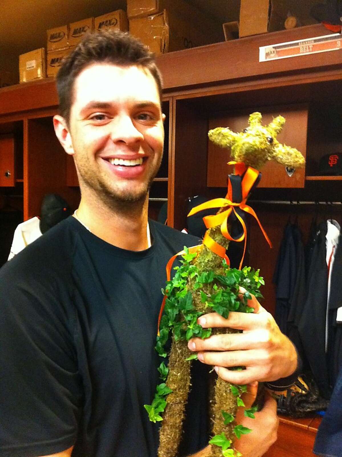 Brandon Belt poses on Aug. 25, 2011, in the Giants' clubhouse with a giraffe of ivy and moss made for him by a Marin County florist.