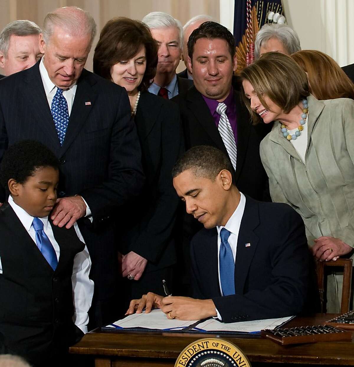 US President Barack Obama, surrounded by lawmakers and guests, signs the healthcare insurance reform legislation during a ceremony in the East Room of the White House in Washington on March 23, 2010. Obama signed into law his historic health care reform, enacting the most sweeping social legislation in decades which will ensure coverage for almost all Americans. AFP PHOTO / Saul LOEB (Photo credit should read SAUL LOEB/AFP/Getty Images) Ran on: 03-24-2010 President Obama signs the health care overhaul bill surrounded by officials, guests and Marcelas Owens, 11, of Seattle, who began campaigning for the bill after his uninsured mother died of pulmonary hypertension. Ran on: 03-24-2010 President Obama signs the health care overhaul bill surrounded by officials, guests and Marcelas Owens, 11, of Seattle, who began campaigning for the bill after his uninsured mother died of pulmonary hypertension. Ran on: 04-04-2010 President Obama signs the health care insurance reform bill in the East Room of the White House. At left is Marcelas Owens, 11, of Seattle, who began campaigning for the bill after his uninsured mother died of hypertension. Ran on: 04-04-2010 President Obama signs the health care insurance reform bill in the East Room of the White House. At left is Marcelas Owens, 11, of Seattle, who began campaigning for the bill after his uninsured mother died of hypertension. Ran on: 12-26-2010 President Obama and House Speaker Nancy Pelsoi passed health care reform, but paid for it in the November election. Ran on: 12-26-2010 President Obama and House Speaker Nancy Pelsoi passed health care reform, but paid for it in the November election. Ran on: 03-20-2011 President Obama signed the health care overhaul legislation last March. The bills proponents said it would increase access to the system for...