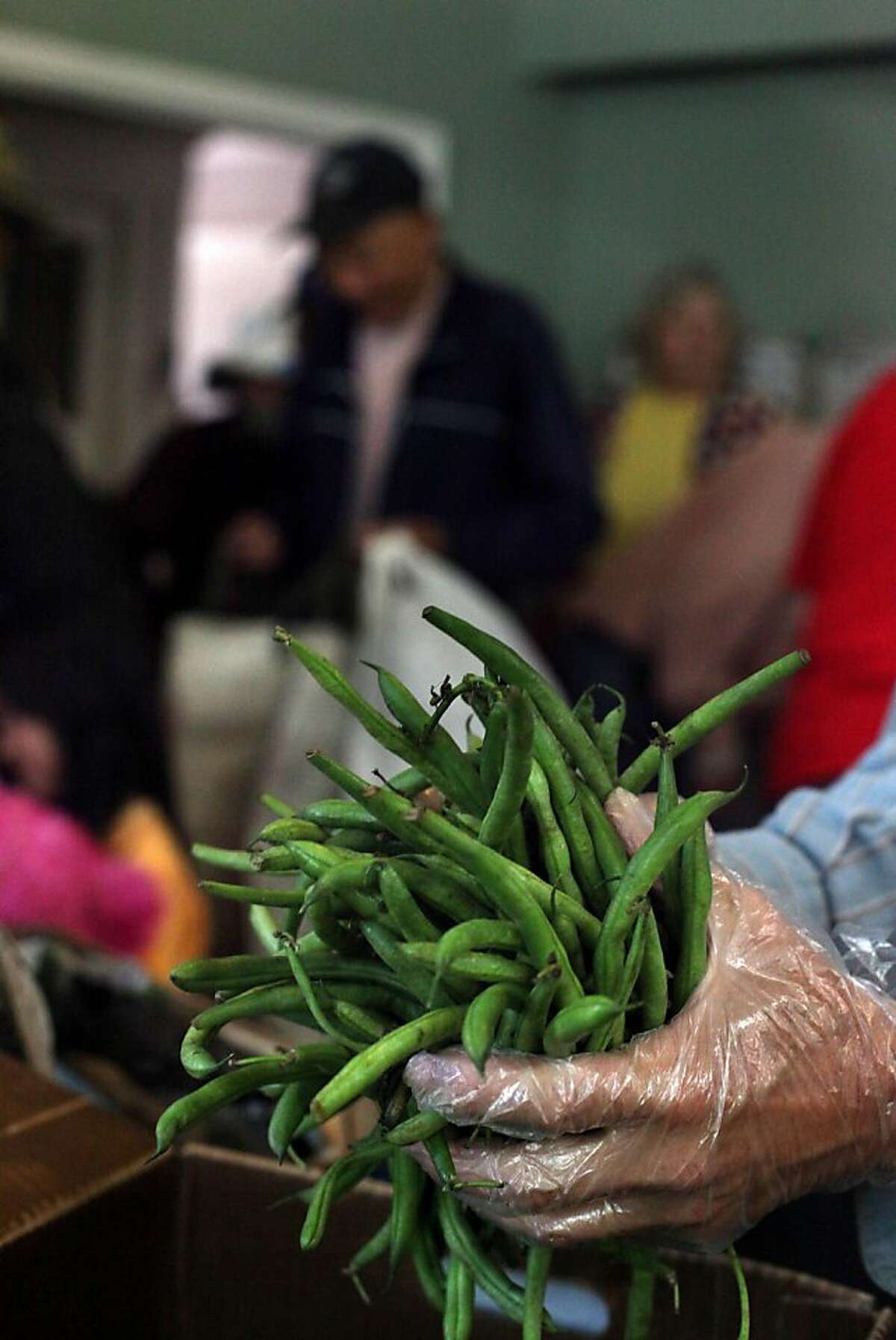 A volunteer prepares to pass out handfuls of green beans at Hosana Celebration Center on Tuesday, August 9, 2011 in San Francisco, Calif. The food is provided to the center by the San Francisco Food Bank.