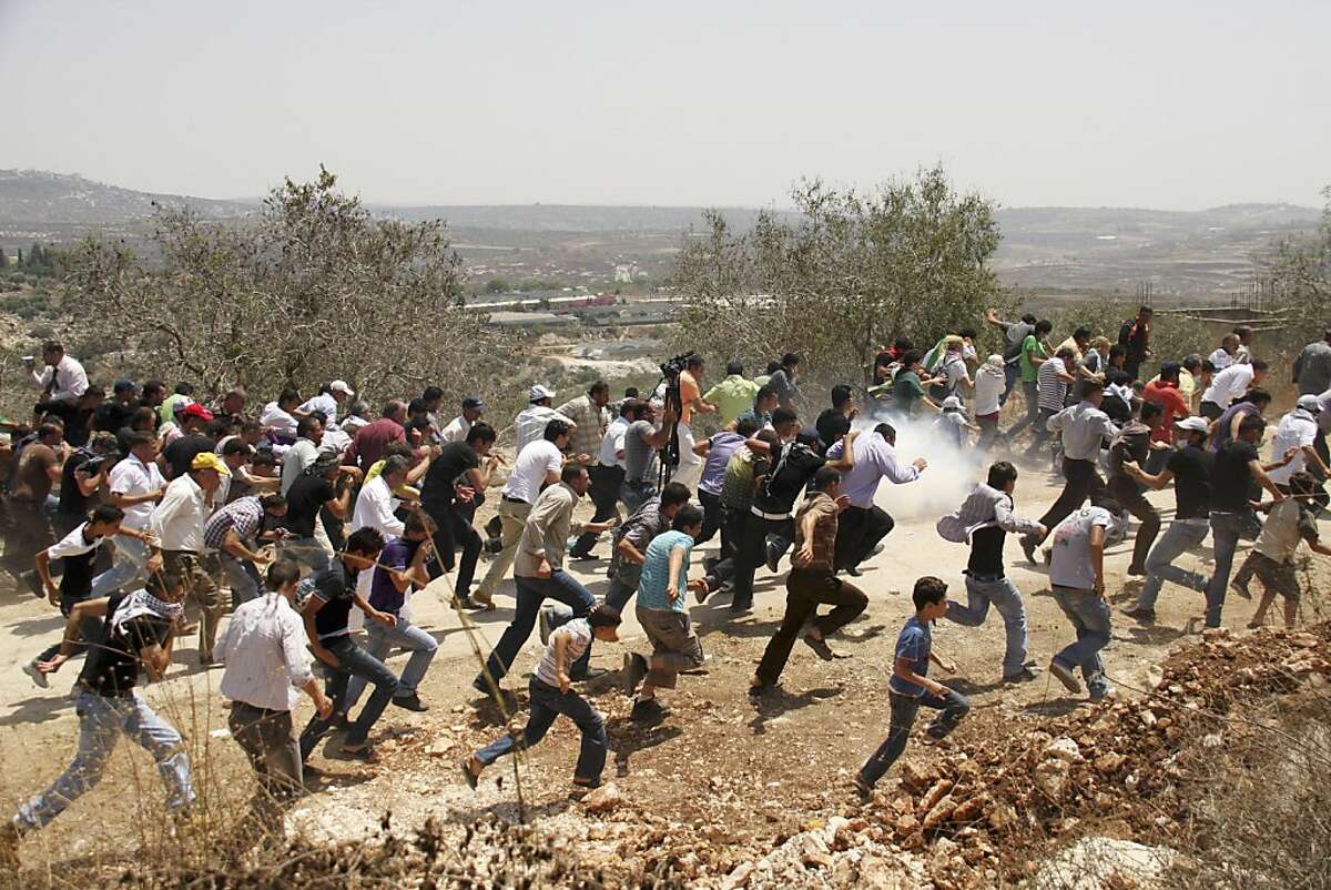 Palestinians run away from tear gas fired by Israeli security forces, during a protest in the village of Kufr Qaddum near the Israeli settlement of Kdumim, in the northern West Bank Friday, July 29, 2011. The protest concerned Palestinian access to lands in the area. (AP Photo/Nasser Ishtayeh)