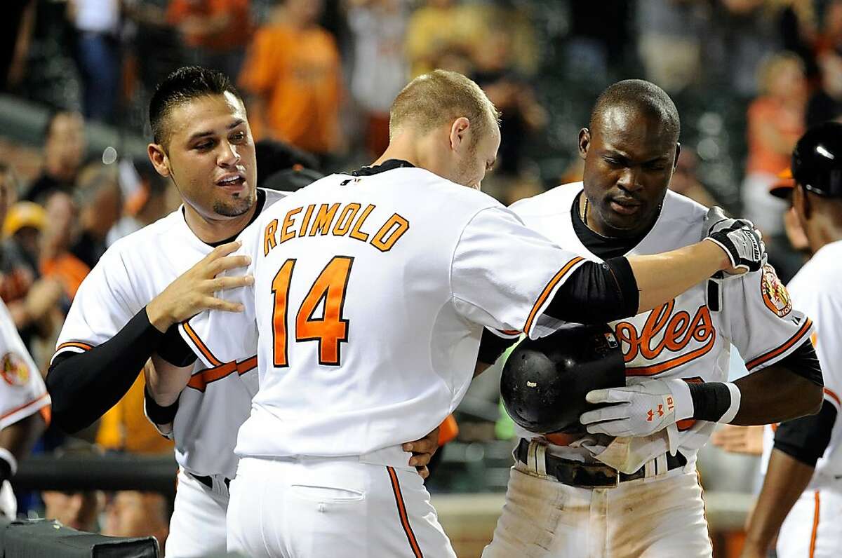 BALTIMORE, MD - AUGUST 10: Nolan Reimold #14 of the Baltimore Orioles celebrates with Felix Pie #18 and Robert Andino #11 after hitting the game winning home run in the tenth inning against the Chicago White Sox at Oriole Park at Camden Yards on August 10, 2011 in Baltimore, Maryland. The Orioles won the game 6-4.