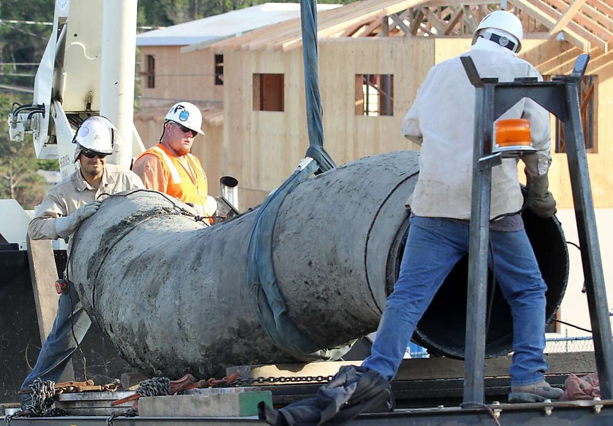 Workers place an eight foot section of gas pipeline that was dug out of the ground on a truck bed on Glenview Dr. in San Bruno on Friday, July 29, 2011. The gas line was dug out so that it can be analyzed in an effort to gain information about last year's deadly blast that occurred a few hundred yards away.