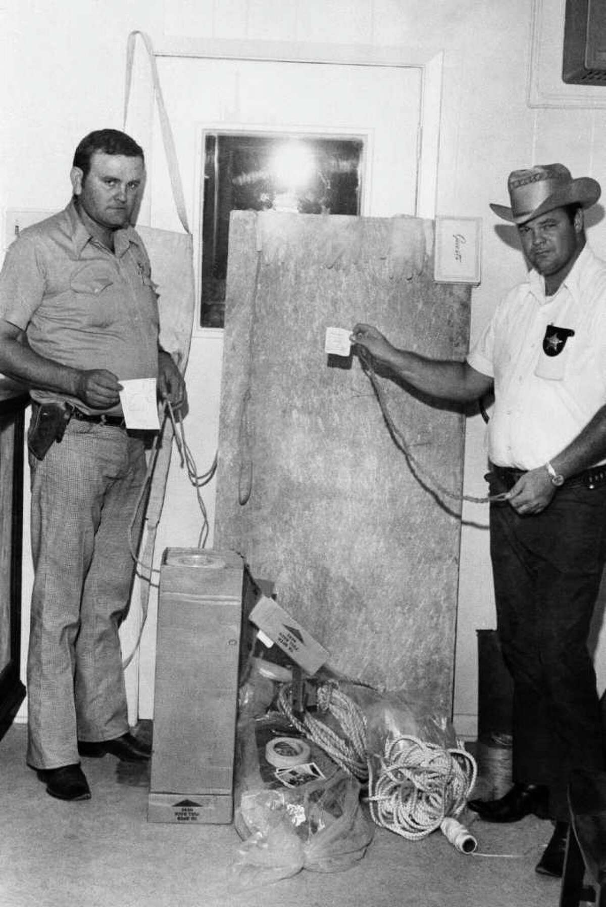 San Augustine County Sheriff deputies, Robert McCroskey, left and Charles Martin, display torture implements found inside and under a cabin on Aug.15, 1973, Broaddus, Texas. The cabin was owned by the parents of Dean Corll, allegedly the central figure in the nations worst mass slaying case. The items included three pairs of plastic gloves, shovels, sacks of lime, rope and a torture board. Owners of cabins nearby say Elmer Wayne Henley, 17, and David Owen Brooks, 18, also alleged connected with the slayings were frequent visitors at the cabin. (AP Photo)