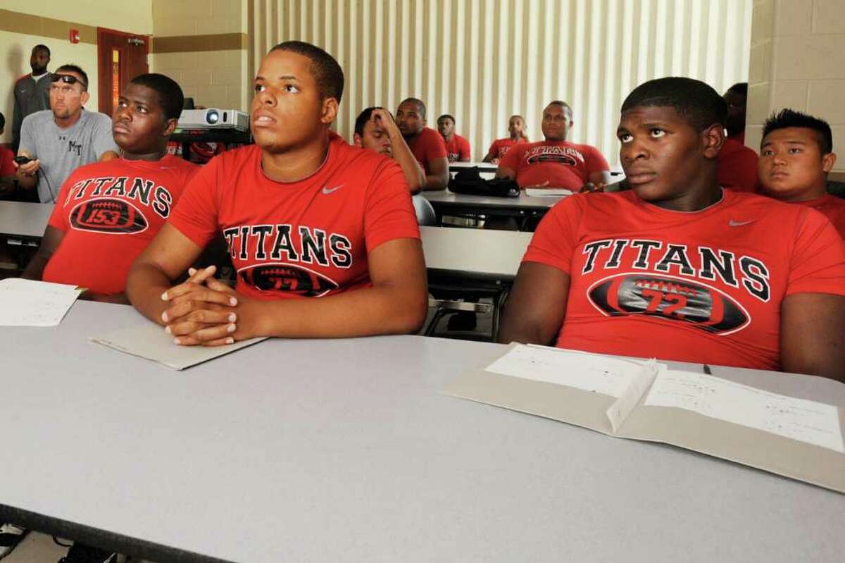 Memorial offensive linemen, Michael Reynolds, left, Creig Carter, center, and Tre'Von Armstead, right, review game footage with assistant coach Kip McFarlin, far left, prior to their Friday night game against Central at the BISD Thomas Center. Tuesday, August 23, 2011. Valentino Mauricio/The Enterprise