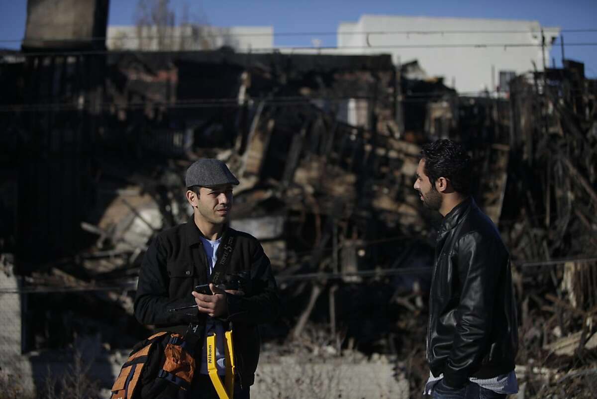 Milad Yazdanpanah (l to r) and Hooman Shahrokhi talk while taking photos of the building they lived in from a roof top across the street on Wednesday, November 30, 2011 in Berkeley, Calif. Yazdanpanah and Shahrokhi lived in the building on the corner of Telegraph Avenue and Haste Street which burned in a five alarm fire on November 18. They had heard a rumor that the building demolition might be in violation of what was agreed upon with the city of Berkeley and went to check it out.