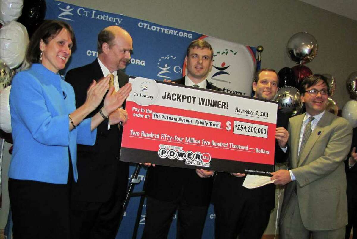 Documents from the Connecticut Lottery Corp. reveal that the winning ticket for last month’s $254 million Powerball jackpot was sold a day before the drawing and signed by Tim Davidson, one of three Greenwich wealth managers who signed a sworn affidavit that they are the sole beneficiaries of the record-setting prize. Davidson, second left, is pictured receiving a ceremonial check with the other two winners, Greg Skidmore, center, and Brandon Lacoff, second right, after the men claimed the jackpot Nov. 28. (AP Photo/Connecticut Lottery)