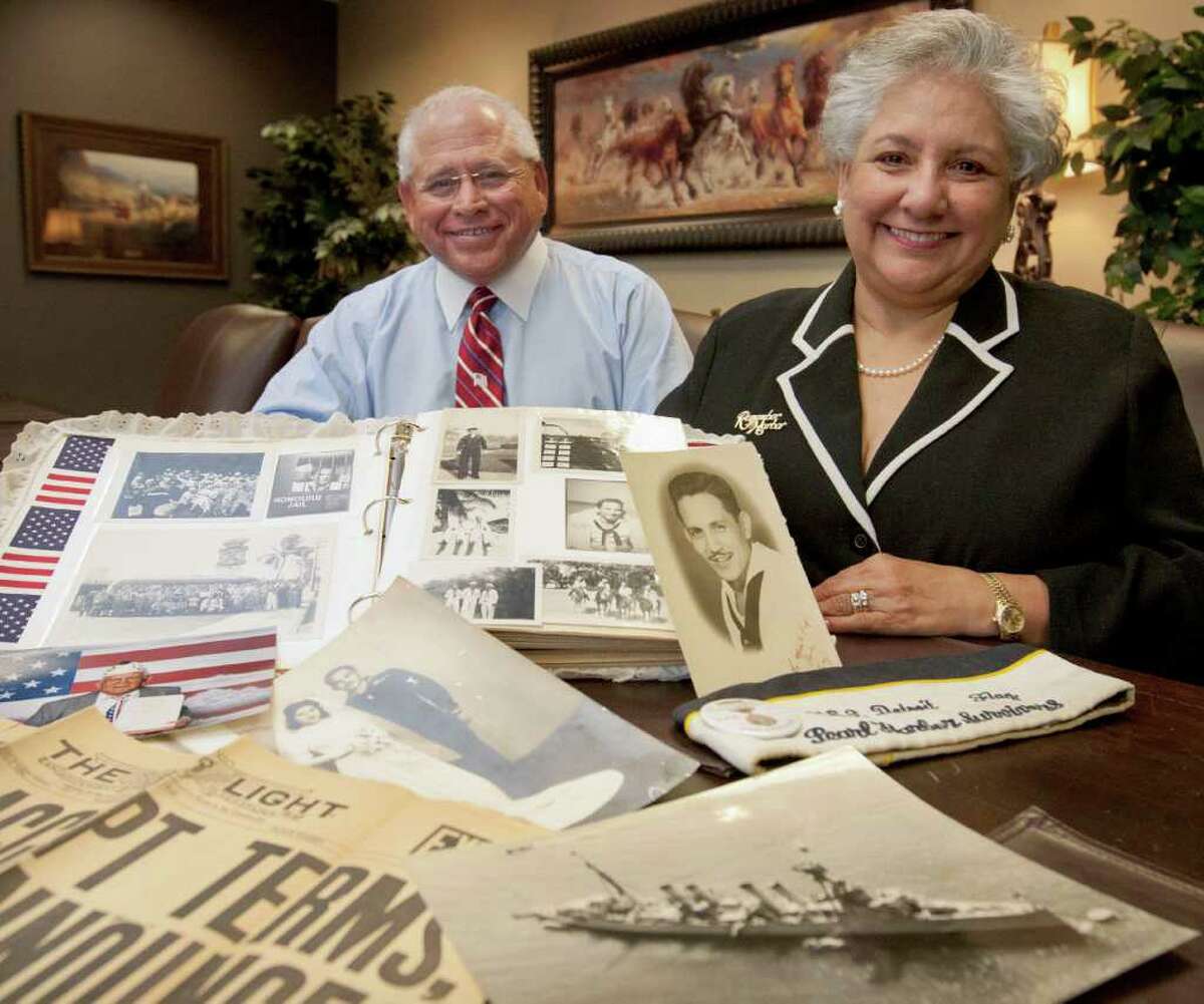 Ron Botello, left, and Irene Botello Hernandez, pose with mementos and photographs of their late father, Pearl Harbor survivor Raynaldo Botello, Tuesday, Dec. 6, 2011, in San Antonio.