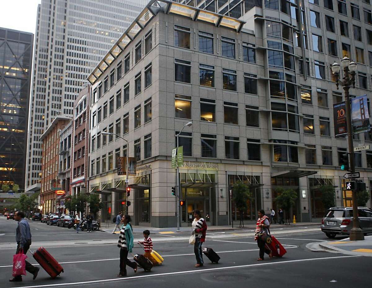 A family walks past the office tower at 150 California Street that was built next to a row of much older buildings in the financial district of San Francisco Calif., on July 22, 2011.