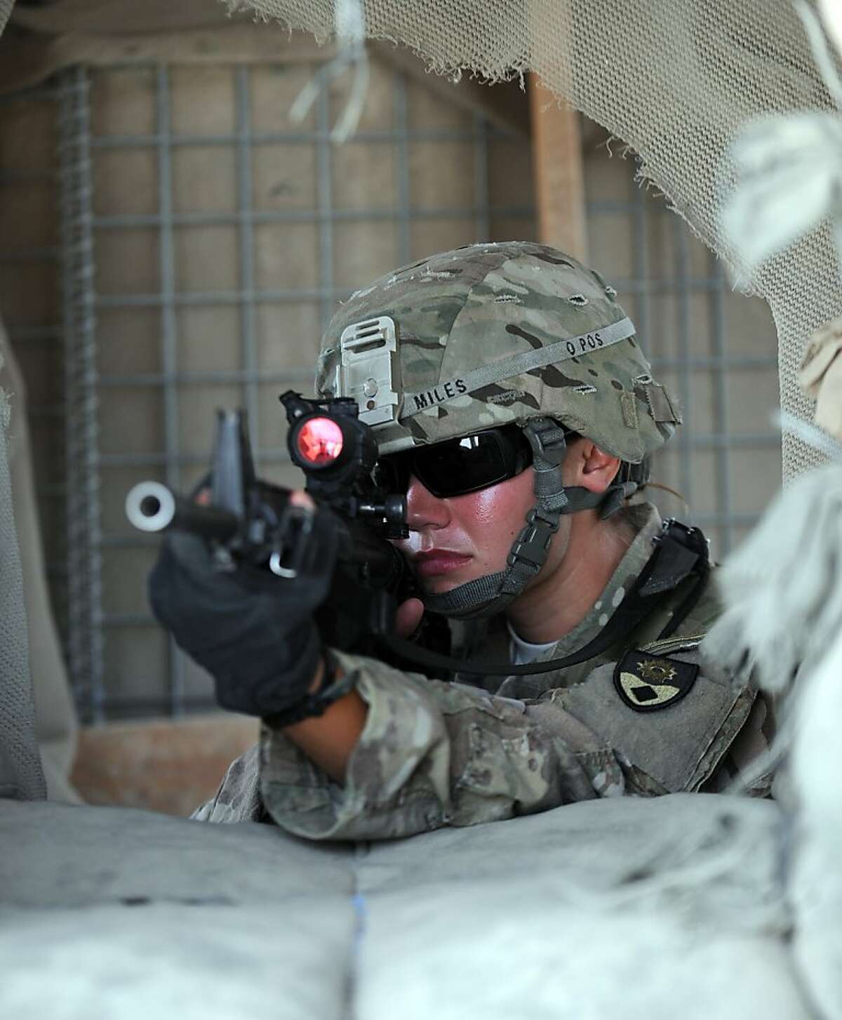 US soldier SPC Jessie Miles looks through the visor of her weapon from a watch tower at camp Clark in Mandozai district, Khost province in eastern Afghanistan on July 9, 2011. A planned US troop withdrawal from Afghanistan will start slowly this summer with about 800 soldiers in two Army units due to depart this month, US officers said July 7.