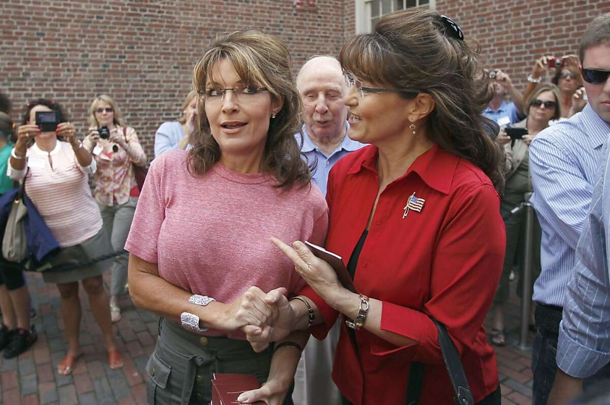 Former Alaska Gov. Sarah Palin, left, poses with celebrity look-alike impersonator Cecilia Thompson during a tour of Boston's North End neighborhood, Thursday, June 2, 2011. Palin's father Chuck Heath is at center.