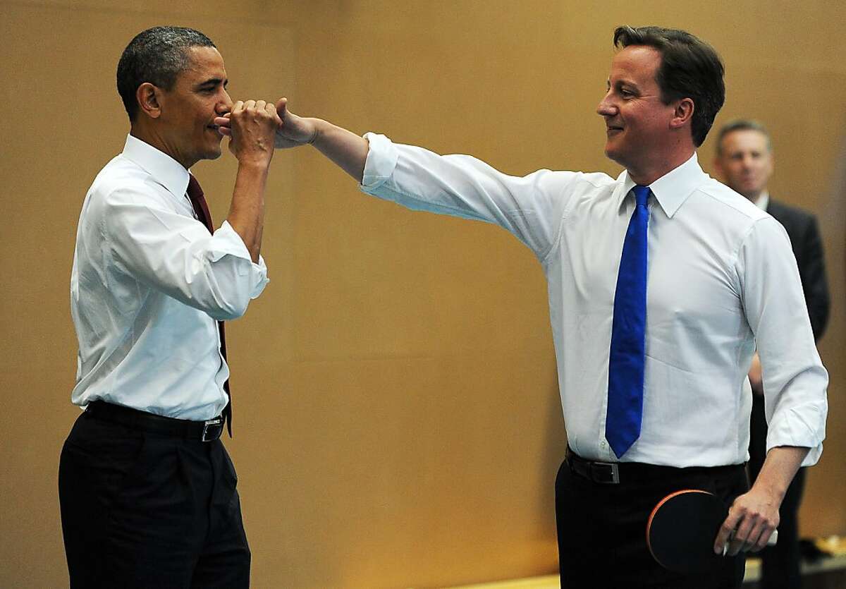 US President Barack Obama (L) high-fives with British Prime Minister David Cameron (R) as they play table tennis with students of the Globe Academy school in London, on May 24, 2011.