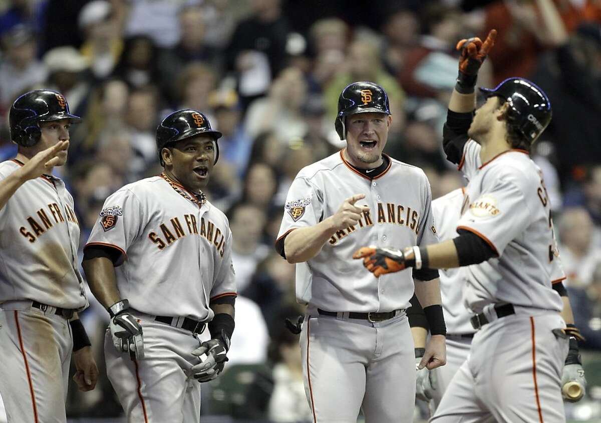 San Francisco Giants' Brandon Crawford, right, points to the sky as he celebrates with teammates, from left to right, Nate Schierholtz, Miguel Tejada and Aubrey Huff after all four scored on Crawford's grand slam during the seventh inning of a baseball game against the Milwaukee Brewers Friday, May 27, 2011, in Milwaukee.
