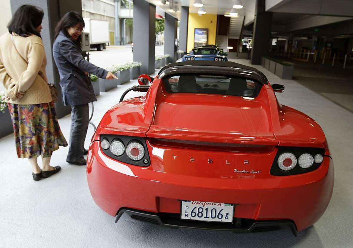 People look at a Tesla Motors Roadster in a garage in San Jose, Calif., Wednesday, May 25, 2011. Tesla says it plans to raise up to $214.3 million by selling common stock, partly to fund development of a crossover vehicle as it seeks to expand its offerings beyond its Roadster sports car.