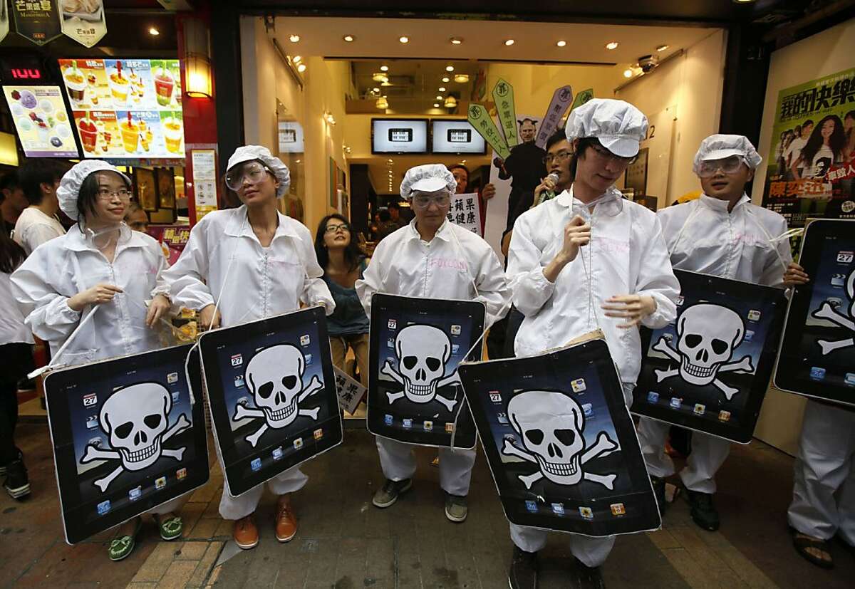 FILE - In this file photo taken Saturday, May 7, 2011, local and mainland Chinese university students, dressed as the Foxconn workers, hold mock iPads with a skeleton print outside an Apple Premium Reseller shop in Hong Kong. An explosion that occurred onMay 20, 2011, at one of two factories that make Apple's new iPad 2 highlights the risks of a global manufacturing strategy that has cut costs but concentrates production in a few locations.