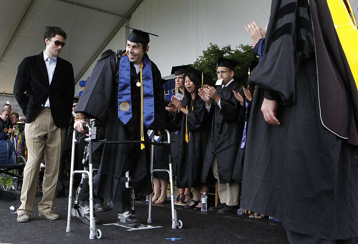 Austin Whitney walks across the stage strapped to exoskeleton legs during commencement ceremonies at UC Berkeley on Saturday. Whitney, who can no longer walk following an auto accident in 2007, walked across the stage wearing the device designed by a UC Berkeley engineering professor and a team of graduate students.