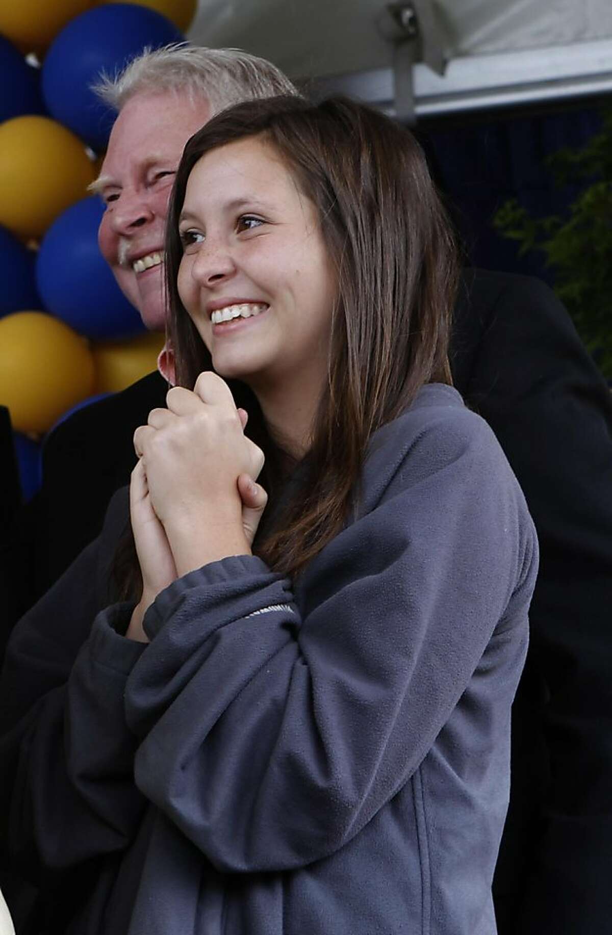 Laura Whitney smiles as her brother Austin walks across the stage during commencement ceremonies at UC Berkeley on Saturday. Austin Whitney, who can no longer walk following an auto accident in 2007, wore an exoskeleton device designed by a UC Berkeley engineering professor and graduate students. In the background at left is their father, Jim.