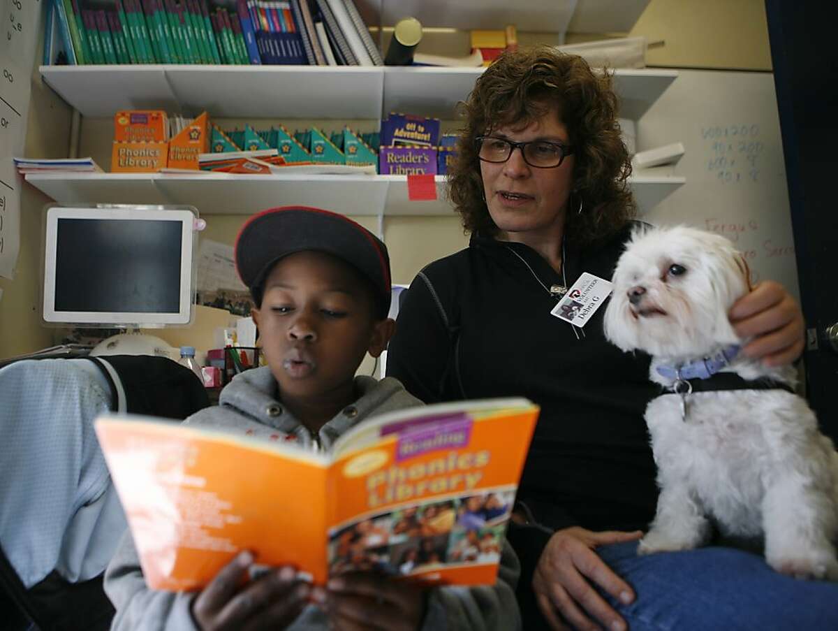 Doug Turner, age 8, a second grader from Junipero Serra Elementary School, reads to a maltese puppy named Sophie from the SPCA with volunteer Debra Greenstein on Wednesday, April 13, 2011.