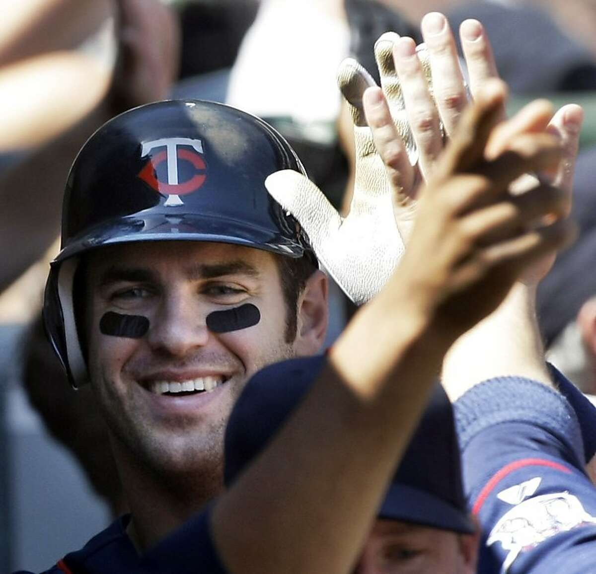 Minnesota Twins' Joe Mauer is congratulated in the the dugout after hitting a grand slam during the sixth inning of a baseball game against the Chicago White Sox in Chicago, Thursday, May 21, 2009. (AP Photo/Charles Rex Arbogast)