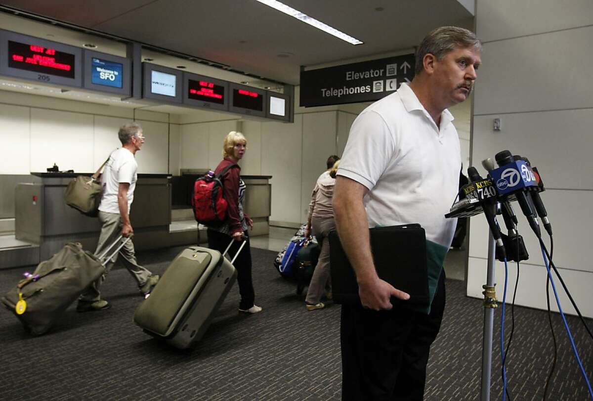Passengers heading for their flights walk past retired police officer Larry Wright as he describes how he took down a disturbed passenger when he rushed the cockpit door on a flight from Chicago on Sunday night, at a news conference at SFO in San Francisco, Calif. on Tuesday, May 10, 2011.