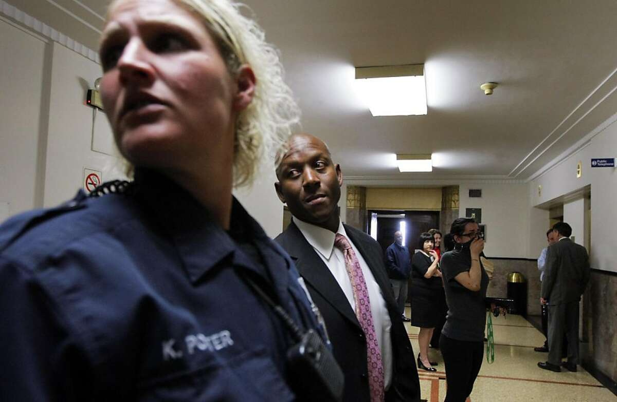 Oakland police department sergeant Derwin Longmire, center and officer K. Potter wait in the lobby outside Judge Thomas M. Reardon courtroom where Longmire is expected to testify in the Chauncey Bailey shooting later, Thursday, April 14, 2011.