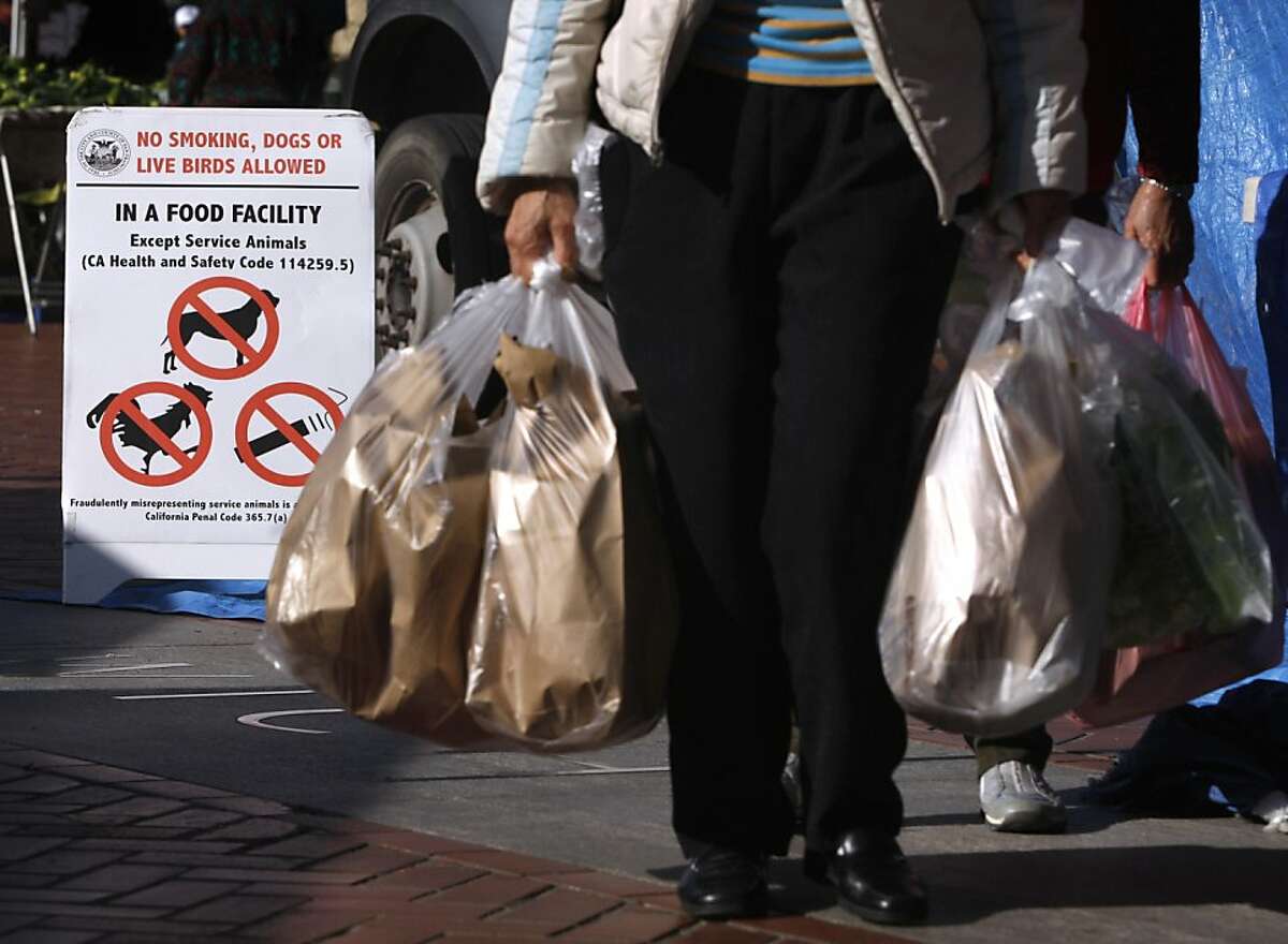 Customers carry bags filled with live birds purchased from the Raymond Young poultry stand at the Heart of the City Farmers' Market in San Francisco, Calif. on Wednesday, May 4, 2011. Signs are posted announcing that sales of live animals will cease at the end of the month.