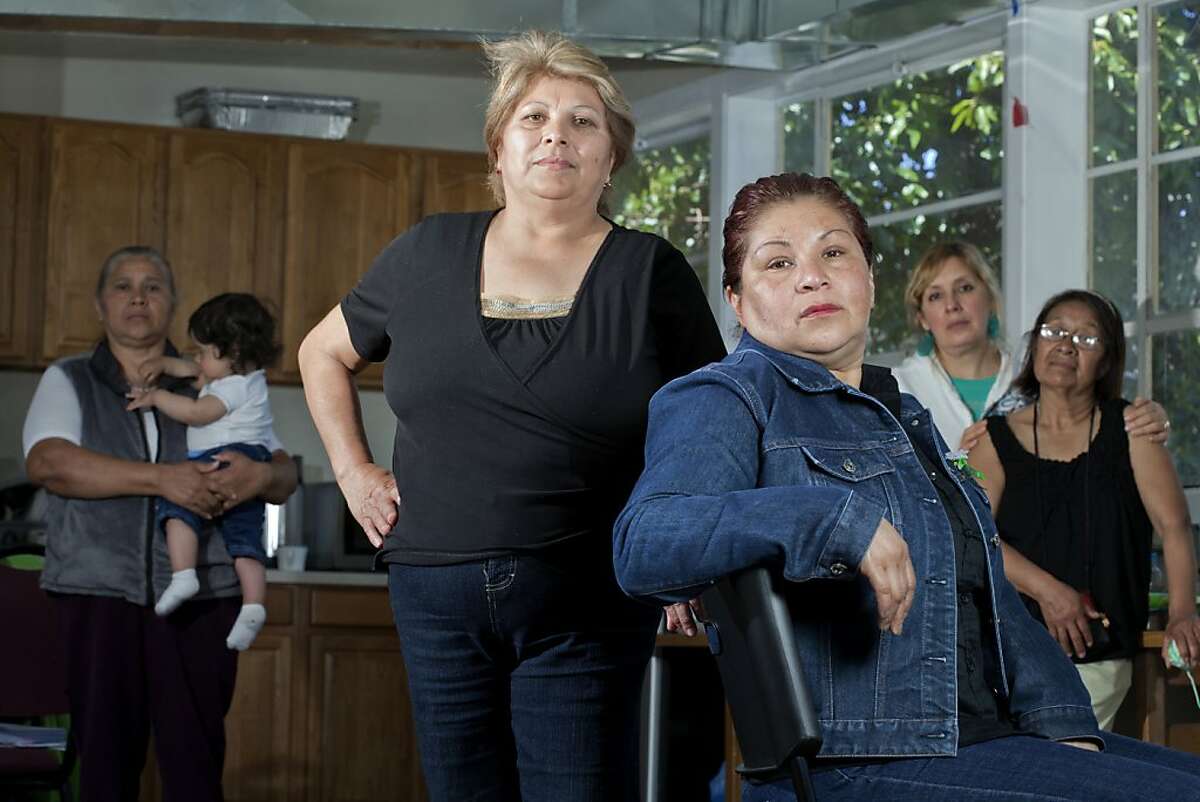 Domestic workers, Maria Luisa Figueroa, left, and Cristina Ceballos, pose for a portrait with other women at Oakland MUA, the headquarters of Mujeres Unidas y Activas, a group that advocates for Latino immigrants in Oakland, Calif. on Tuesday, April 26, 2011. In the background from left, Irene Hernandez holding Lionel Rodriguez, 8 mos., Hortencia Mu?oz and Maria Santiago. Kat Wade / Special to the Chronicle