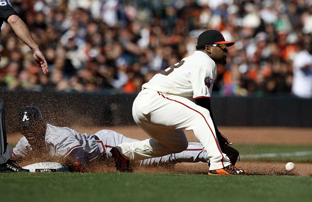 Pablo Sandoval gets a late throw in the 10th inning as Jason Heyward slides into third Sunday.