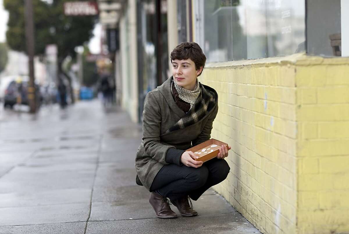 Julie Cloutier poses for a portrait on the corner of 16th and Guerrero Streets next to where she placed a portrait of a rock she collected there as part of an art project in San Francisco, Calif., on Monday, April 25, 2011. Cloutier collected rocks she found on the street, painted portraits of them and then placed the portraits in the precise location where the original rock was found. Her work is part of a group show at San Francisco Art Institute.