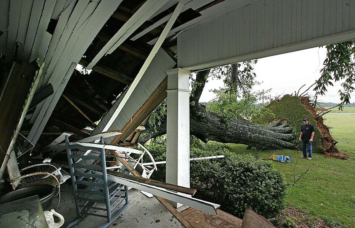 Karl Rhodes looks at the damage to a house in Florence, Ala., after storms caused a large tree to fall on Tuesday, April 26, 2011. The tree crushed a corner bedroom at Beth Scott's home where Rhodes does the grounds-keeping.