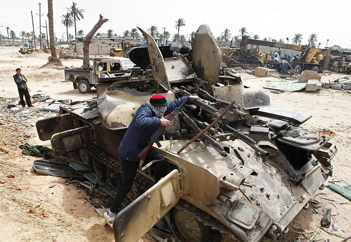A Libyan rebel fighter climbs on a destroyed government armored vehicle in the besieged city of Misrata, the main rebel holdout in Gadhafi's territory, Friday, April 22, 2011.