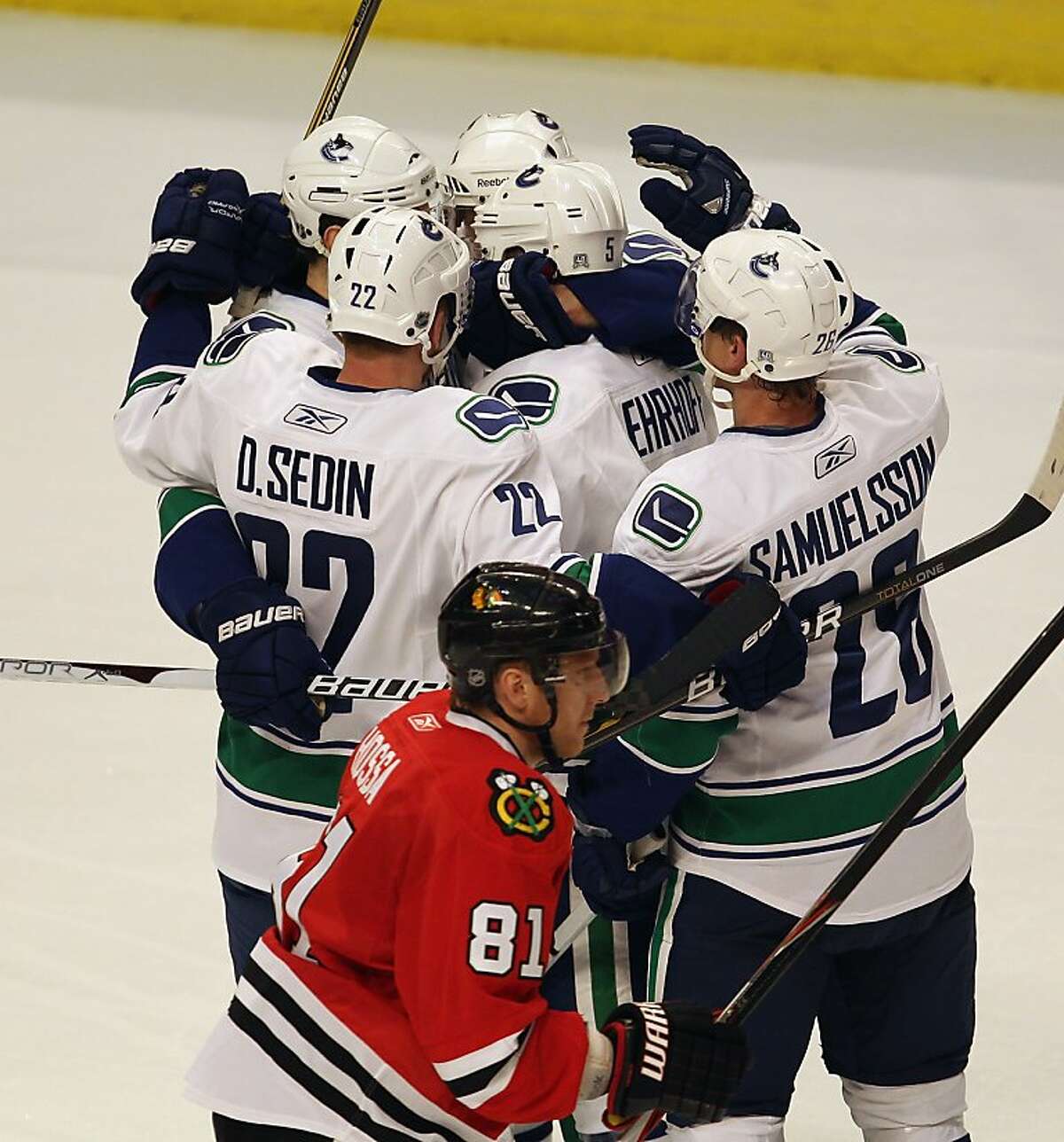 CHICAGO, IL - APRIL 17: Members of the Vancouver Canucks including Daniel Sedin #22 and Mikael Samuelsson #26 celebrate a 2nd period goal by Christian Ehrhoff #5 (center) as Marian Hossa #81 of the Chicago Blackhawks skates off of the ice in Game Three ofthe Western Conference Quarterfinals during the 2011 NHL Stanley Cup Playoffs at the United Center on April 17, 2011 in Chicago, Illinois.