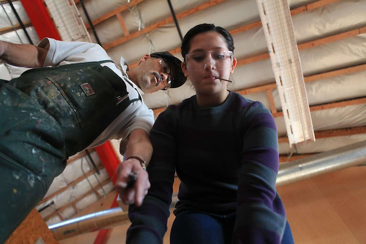 Gus Amador (l to r), carpentry teacher, gives John O'Connell High School junior, Lucerito Martinez, 16, tips while a group of advanced carpentry students work together to rough frame a stage being built in the new industrial arts building at John O'Connell High School on Wednesday, December 7, 2011 in San Francisco, Calif. The stage was being built for a ceremony for the new building to be held the next day.
