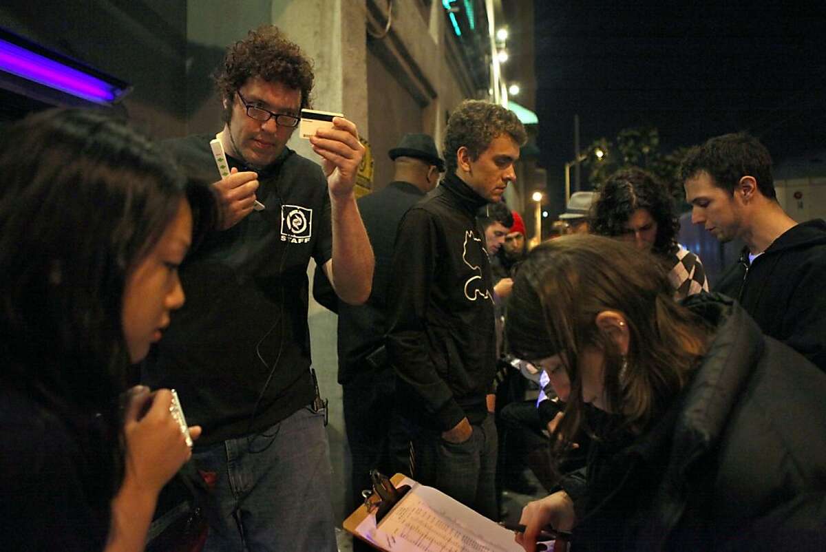 Security staff David Pomije (left) checking identification outside of the entrance of DNA Lounge in San Francisco, Calif., as names are checked on the guest list on Friday, April 15, 2011.