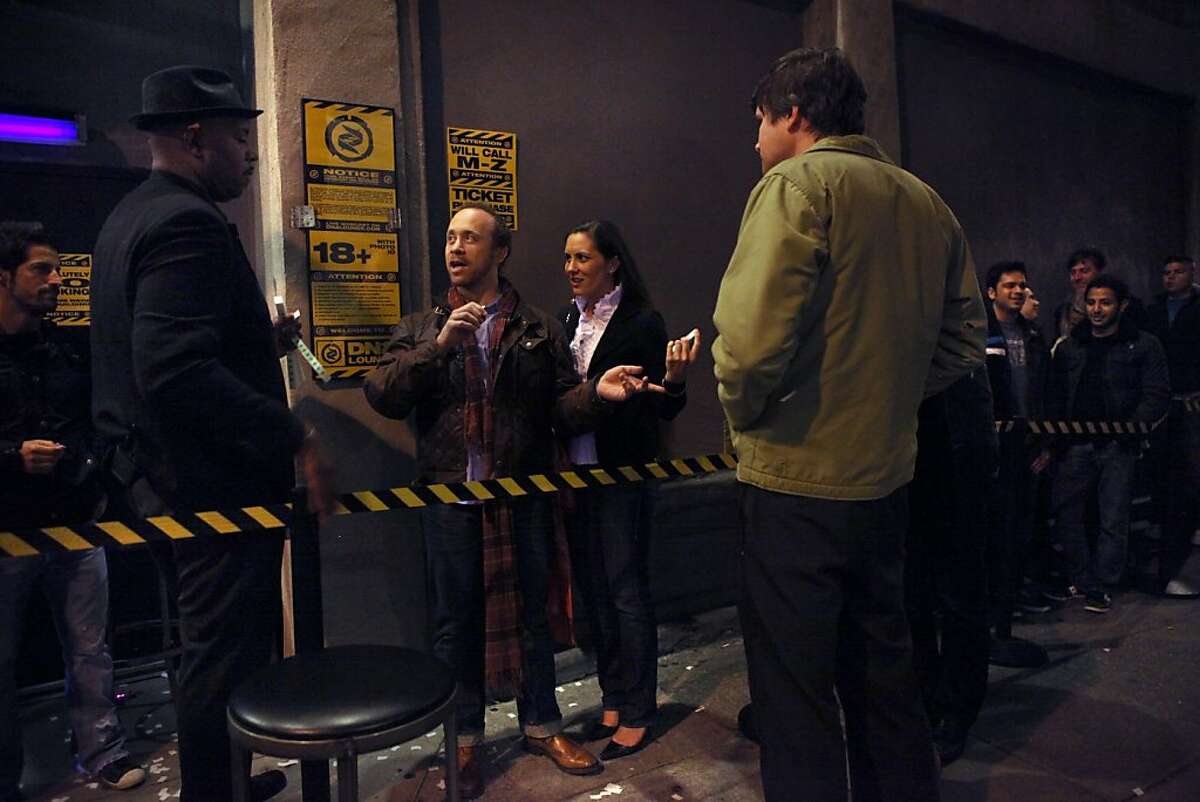 Security staff Sam Craig (left) checking identification of Noah Raizman and Courtney Cutter from Washington outside of the entrance of DNA Lounge in San Francisco, Calif., on Friday, April 15, 2011.