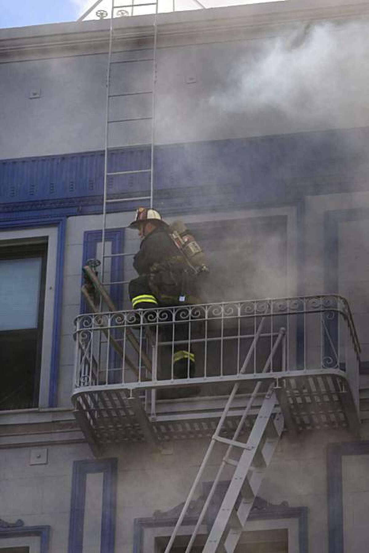 A San Francisco firefighter climbs on a fire escape as others work on a structure fire at 111 Taylor St. on Thursday. The building is a halfway house for parolees.