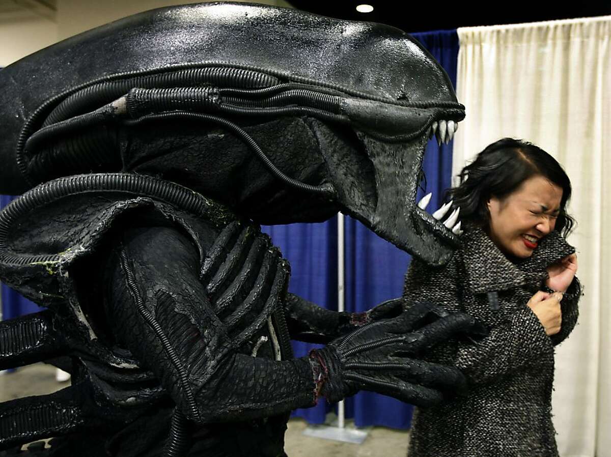 Kristy Huynh recoils from Matthew O'Connor, who is dressed as the "Alien," at the WonderCon comic book convention in San Francisco on Saturday.
