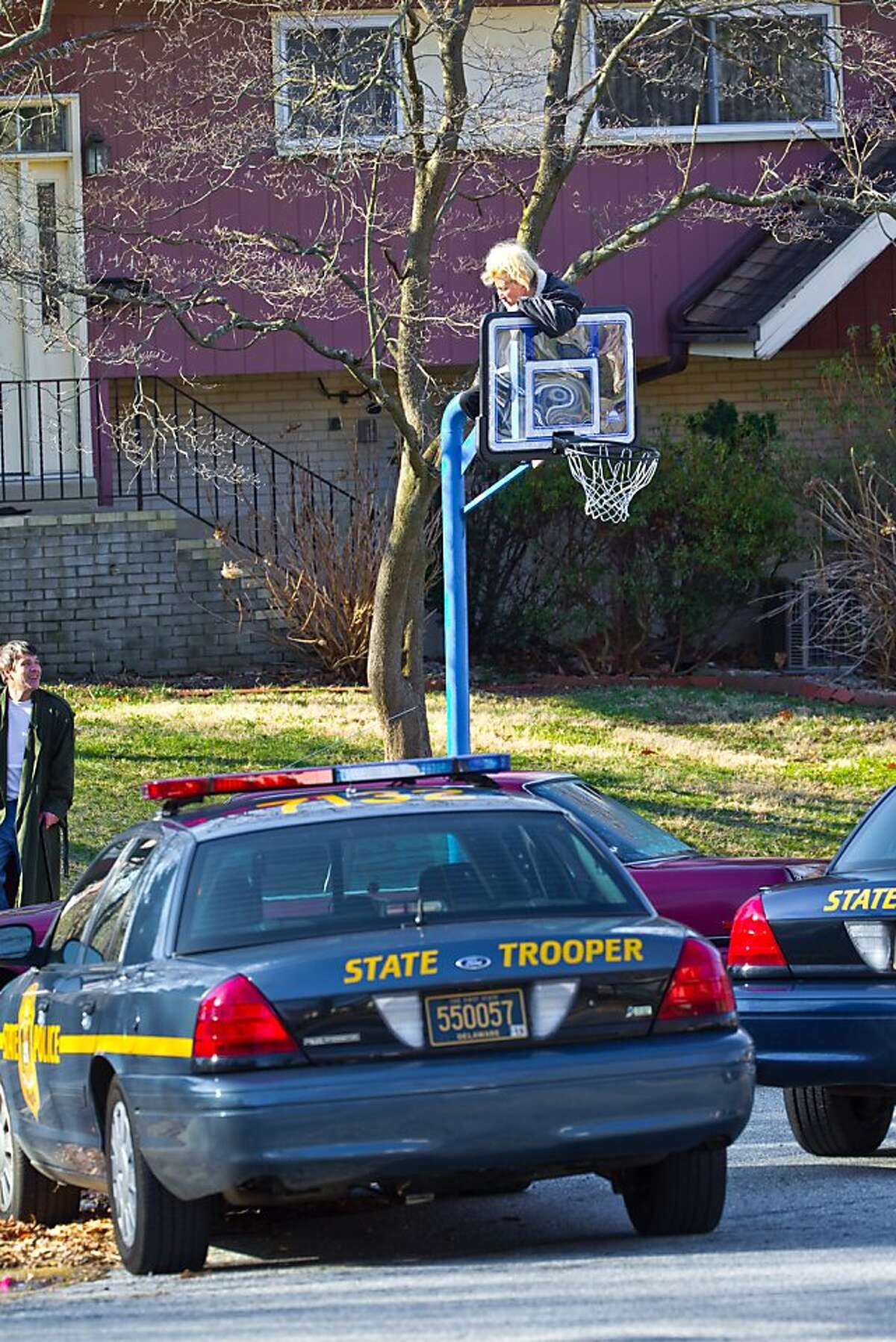 Melissa McCafferty sits on a basketball hoop in protest on after Delaware Department of Transportation crews escorted by state police cruisers tore down basketball hoops, Friday, March 25, 2011, in Claymont, Del. Last fall, DelDOT sent letters to at leasteight residents in the Radnor Green and Ashbourne Hills subdivisions saying their street-side basketball hoops violated the state’s Clear Zone law, which prohibits hoops, trees, shrubs and other objects from being within seven feet of the pavement's edge in subdivisions. DelDOT told residents that if they didn’t take down the hoops that the agency would and residents would be charged for the removal and disposal costs, said Radnor Green resident John McCafferty.
