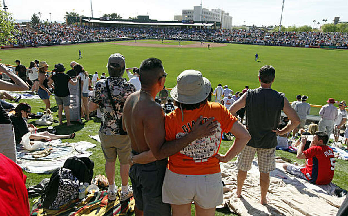 Rawlin and Maggie Castro of San Francisco watch the Giants play the Los Angeles Dodgers from the grassy knoll at Scottsdale Stadium on Saturday.