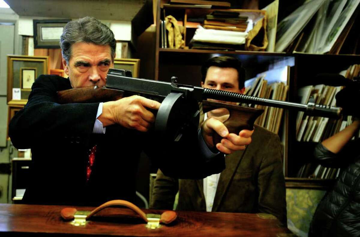 STEPHEN MORTON : NEW YORK TIMES GEARING UP FOR DEBATE?: Texas Gov. Rick Perry, looks down the barrel of a vintage 1928 Thompson submachine gun at the Rhett Gallery in Beaufort, S.C., on Thursday.