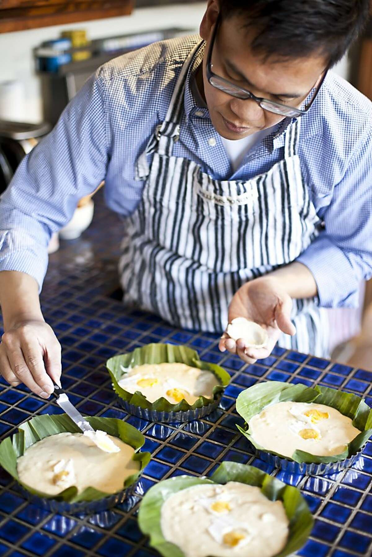 Jun Belen, professional food photographer and blogger, lays thin slices of salted egg on the bibingka batter at his home in Oakland, Calif. on Friday Dec. 2, 2011.