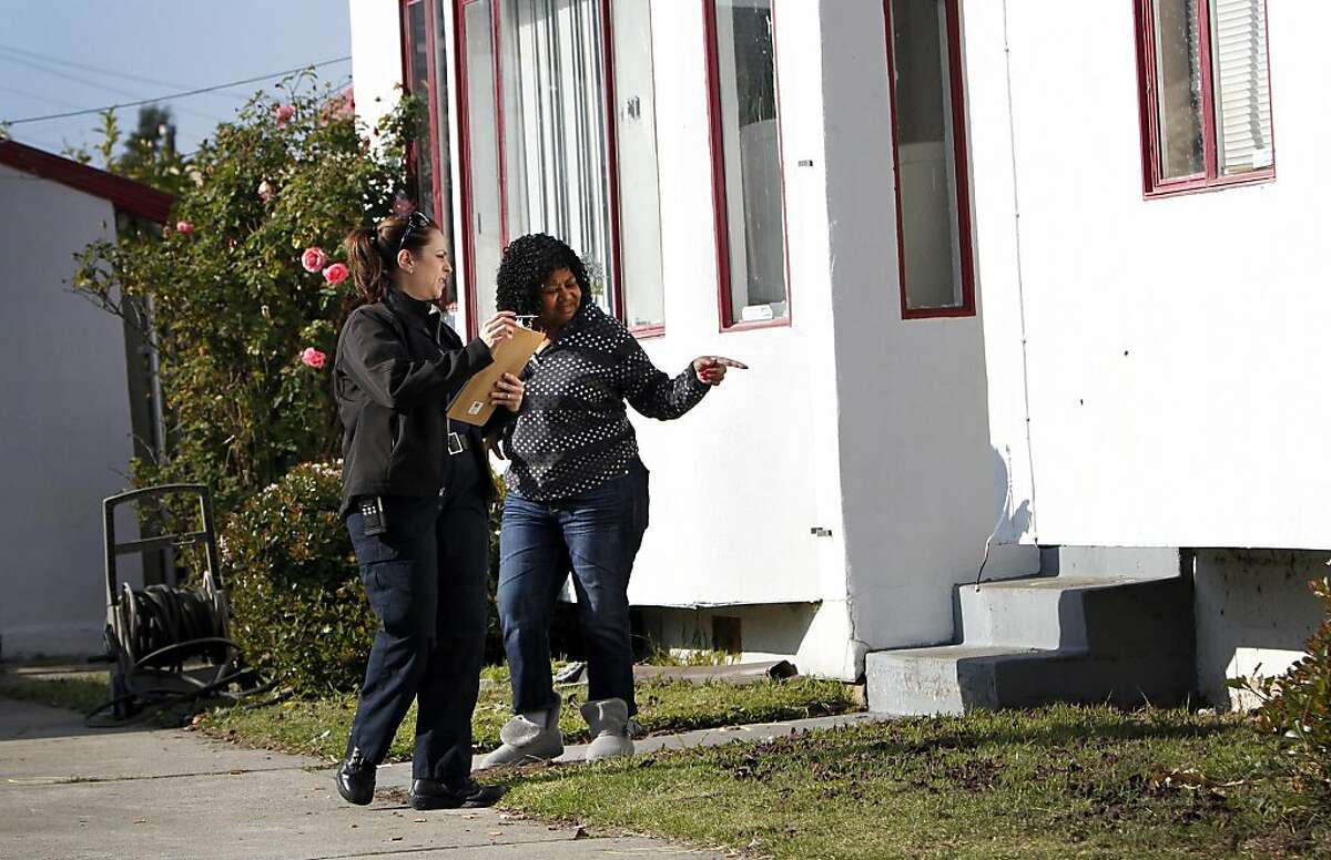 Jean Beal points out bullet holes in the side of her home to an investigator after a home invasion next door ended in gunfire in Richmond, Calif., Thursday, December 8, 2011. A Richmond man allegedly shot two robbers, one fatally, when they broke into his home.