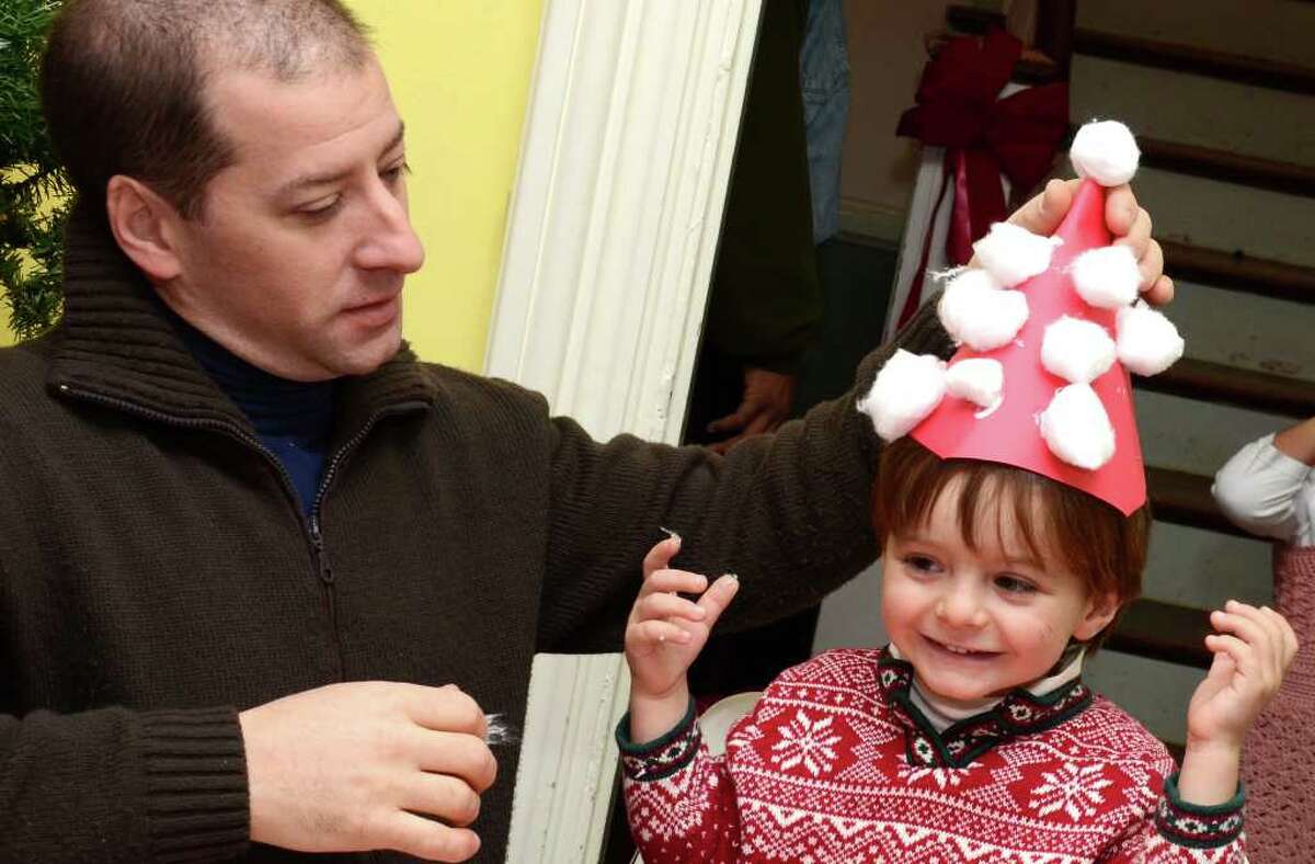 Arthur Zarra, 3, grins as his father, Robert Zarra, of Fairfield, places a construction paper santa hat on his head during the Visit to Santa's House event at the Burr Homestead sponsored by the Junior Women's Club of Fairfield on Sunday, Dec. 11, 2011.