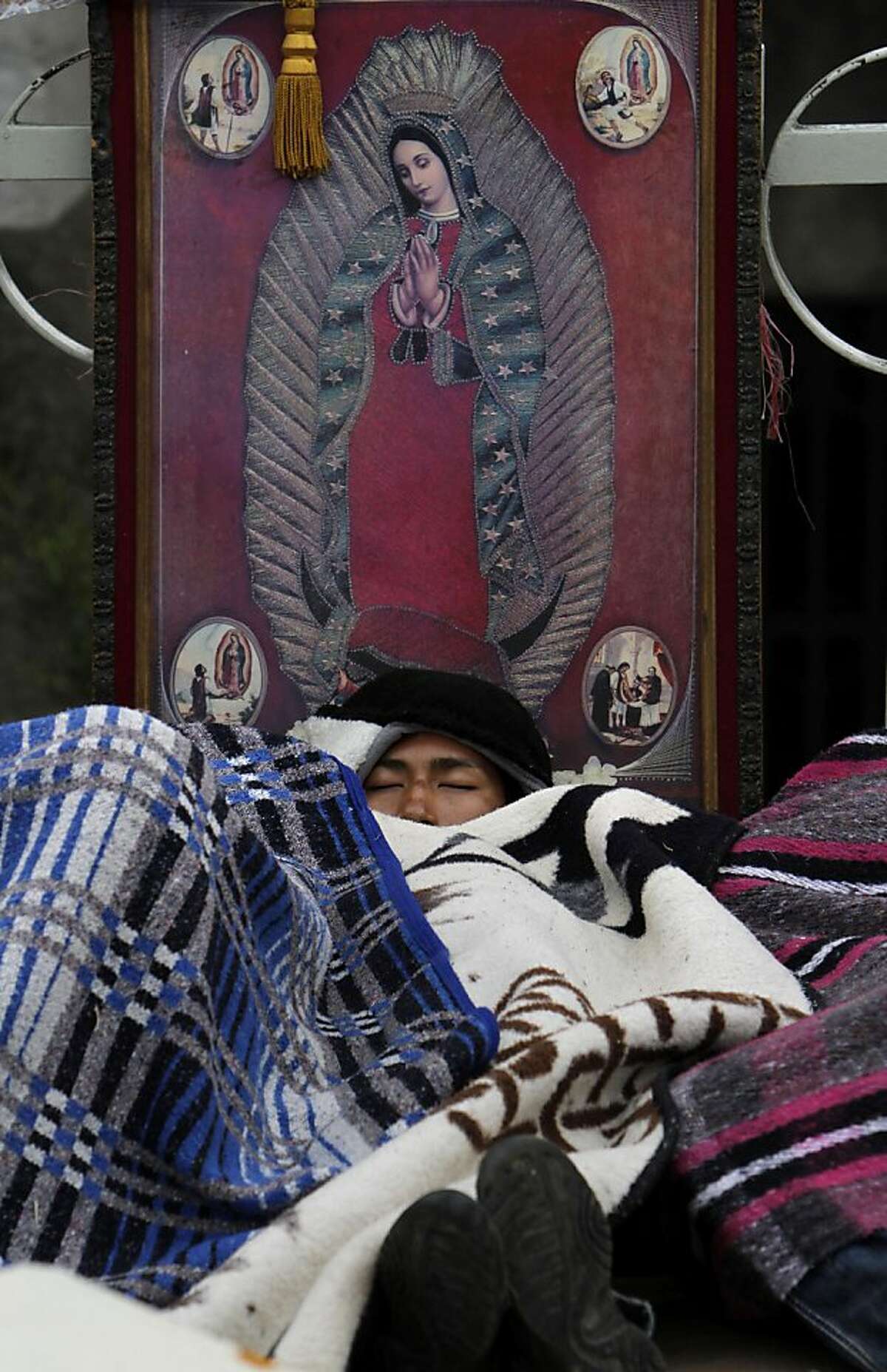 A pilgrim sleeps by an image of the Virgin of Guadalupe outside the Basilica of the Virgin of Guadalupe in Mexico City, Sunday Dec. 11, 2011. Hundreds of thousands of Mexicans are making the pilgrimage to the shrine in anticipation of the Catholic icon's feast day on Dec. 12. Also known as La Morenita, Our Lady of Guadalupe is Mexico's most popular religious and cultural image. (AP Photo/Marco Ugarte)