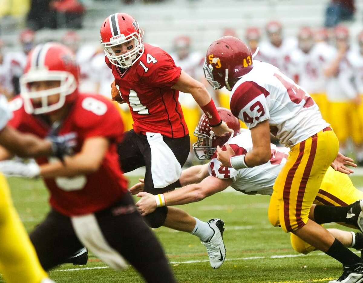 New Canaan High School's #14 Turner Baty, center, runs with the ball as he's pursued by St. Joseph's #14 Tyler Matakevich and #43 Sean Chinova during a football game at New Canaan.