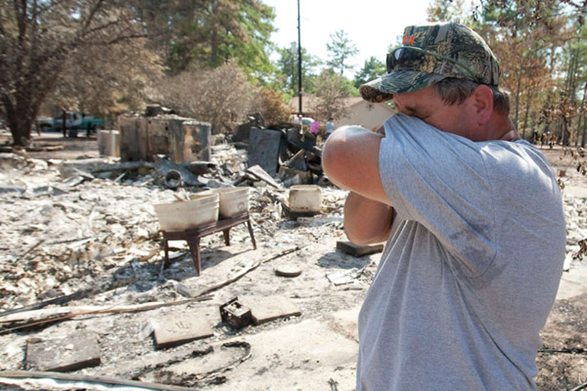 Rocky Barr wipes away a tear as he surveys the remains of his home on Sanders Cemetery Road in Magnolia on Sept. 12. The worst damage was in Bastrop, where two smaller fires joined to form a monster blaze that has destroyed more than 1,550 homes and charred more than 34,000 acres. (AP Photo/The Courier, Karl Anderson)
