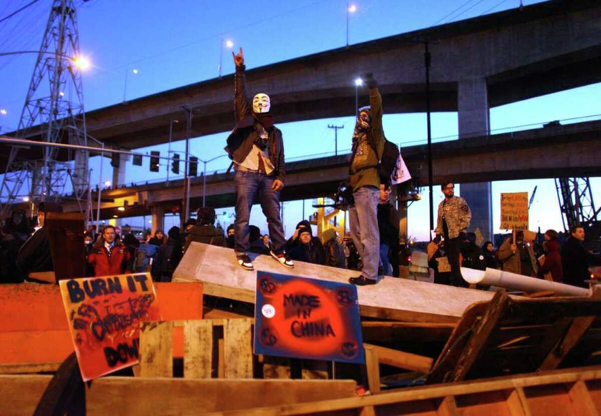 Occupy Seattle protesters stand atop a barricade on Monday, December 12, 2011 at the Port of Seattle. Hundreds of anti-Wall Street protesters gathered at the port and tried to shut down operations. Protesters scuffled with police during the rally and police used pepper spray and two flash-bang grenades to disperse the crowd after a protester threw a lit road flare toward officers. Another threw red paint on officers.