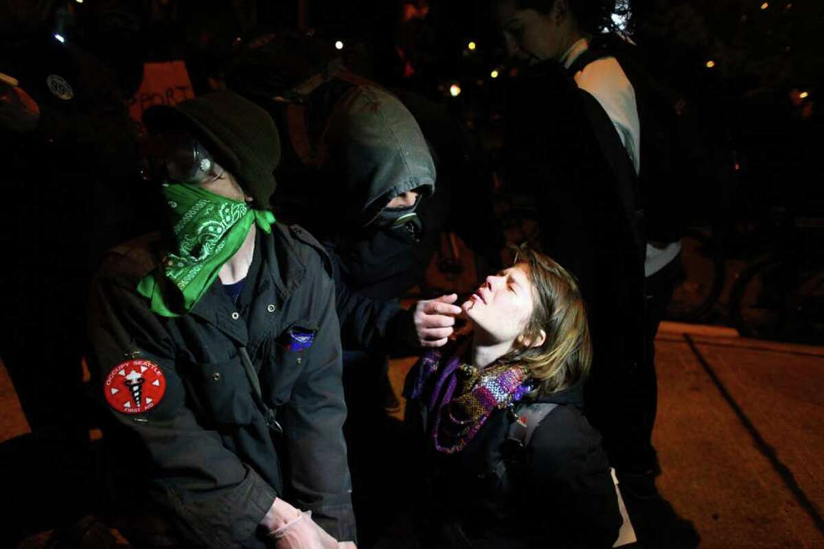 An injured protester is assisted on Monday, December 12, 2011 at the Port of Seattle. Hundreds of anti-Wall Street protesters gathered at the port and tried to shut down operations. Protesters scuffled with police during the rally and police used pepper spray and two flash-bang grenades to disperse the crowd after a protester threw a lit road flare toward officers. Another threw red paint on officers.