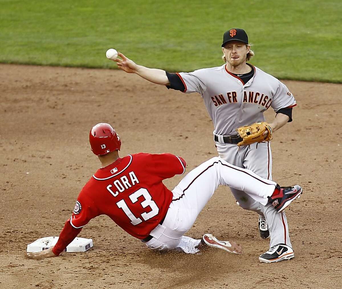 San Francisco Giants shortstop Mike Fontenot attempts a double play as Washington Nationals' Alex Cora (13) is forced out during the ninth inning of an MLB baseball game, Saturday, April 30, 2011 in Washington. The Giants won 2-1. (AP Photo/Luis M. Alvarez)